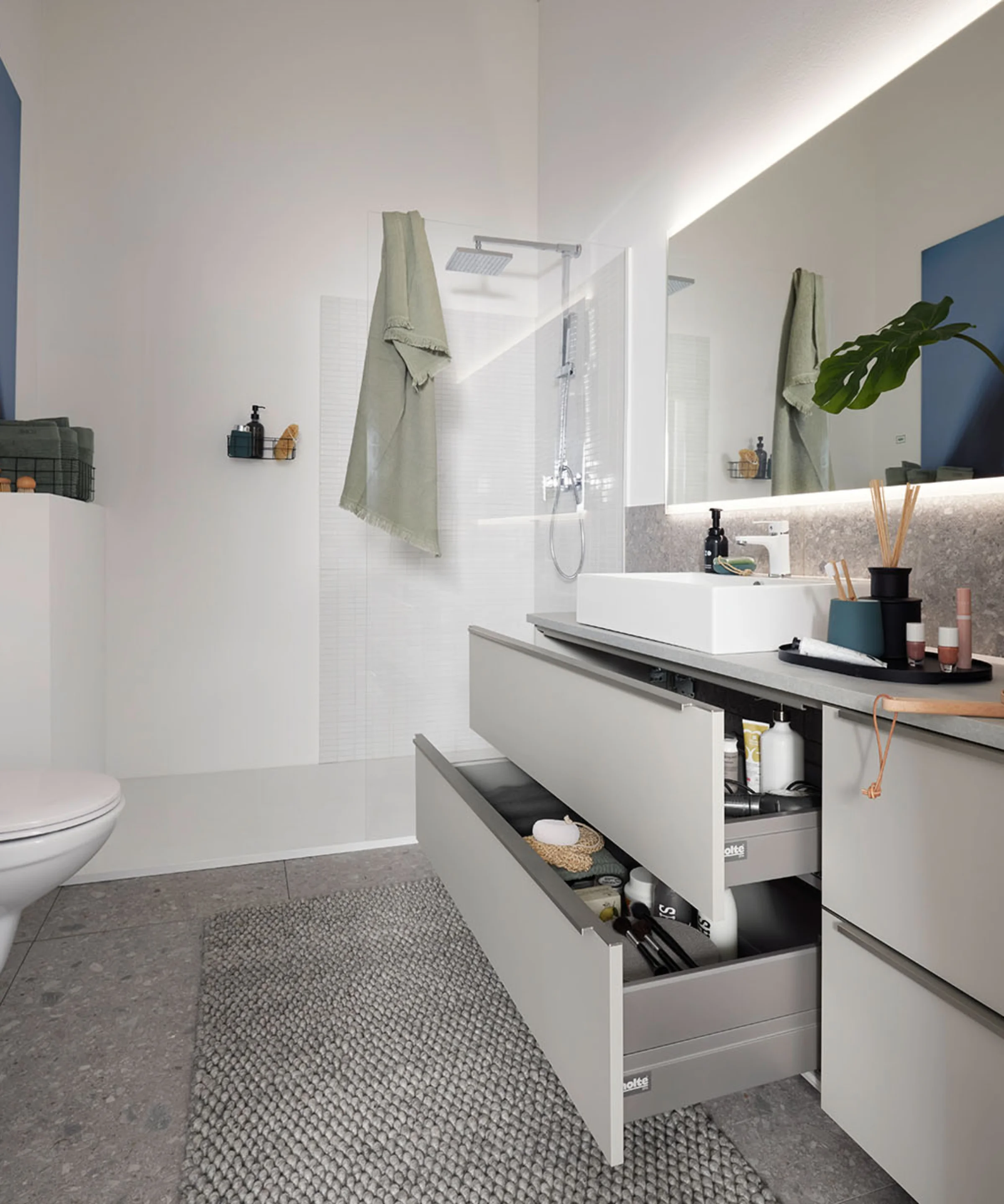 Bagno moderno con grande specchio e cassetto aperto di Nolte SPA.