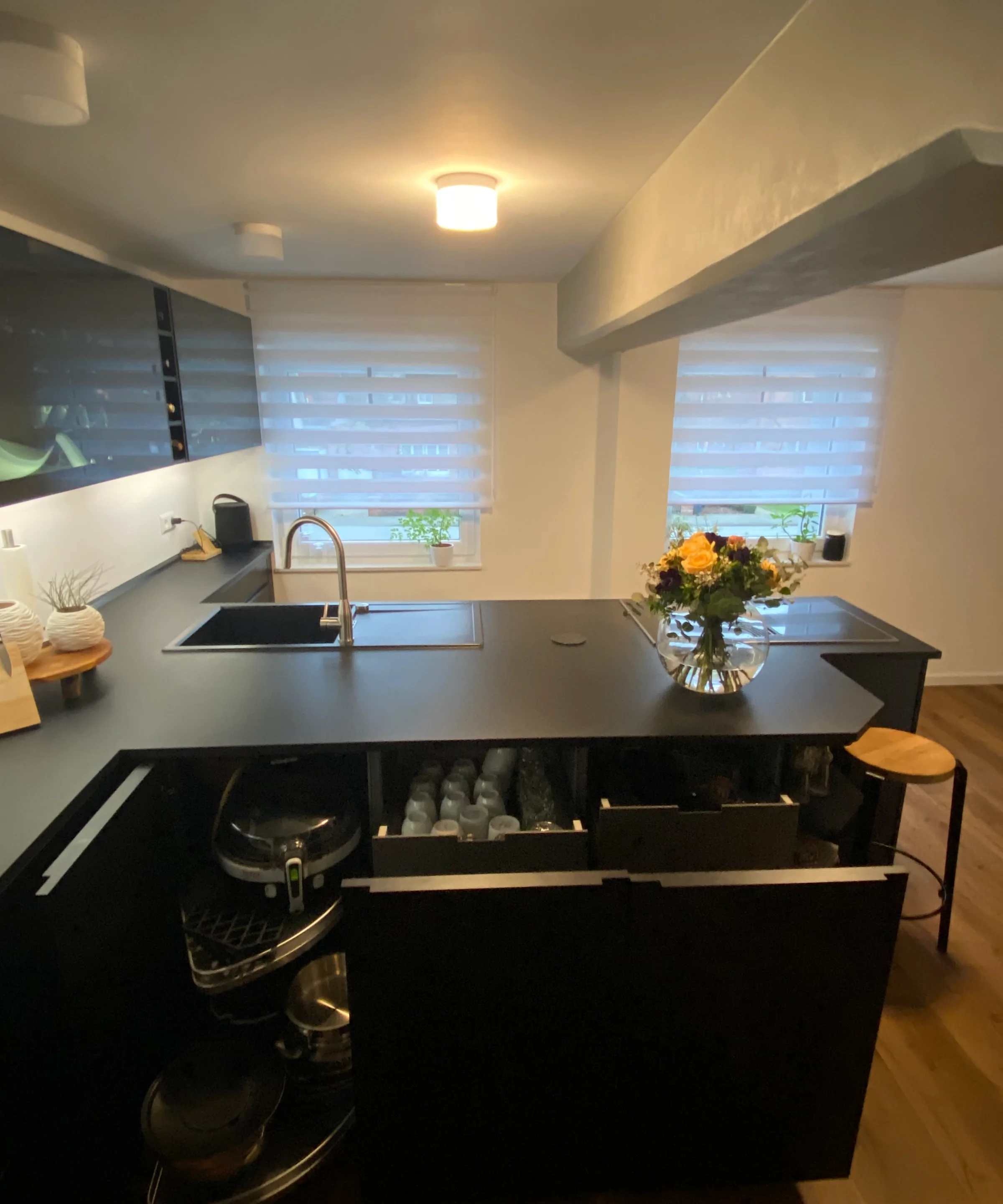 Cucina moderna con armadi scuri e isola, arredata da Nolte Kitchen.