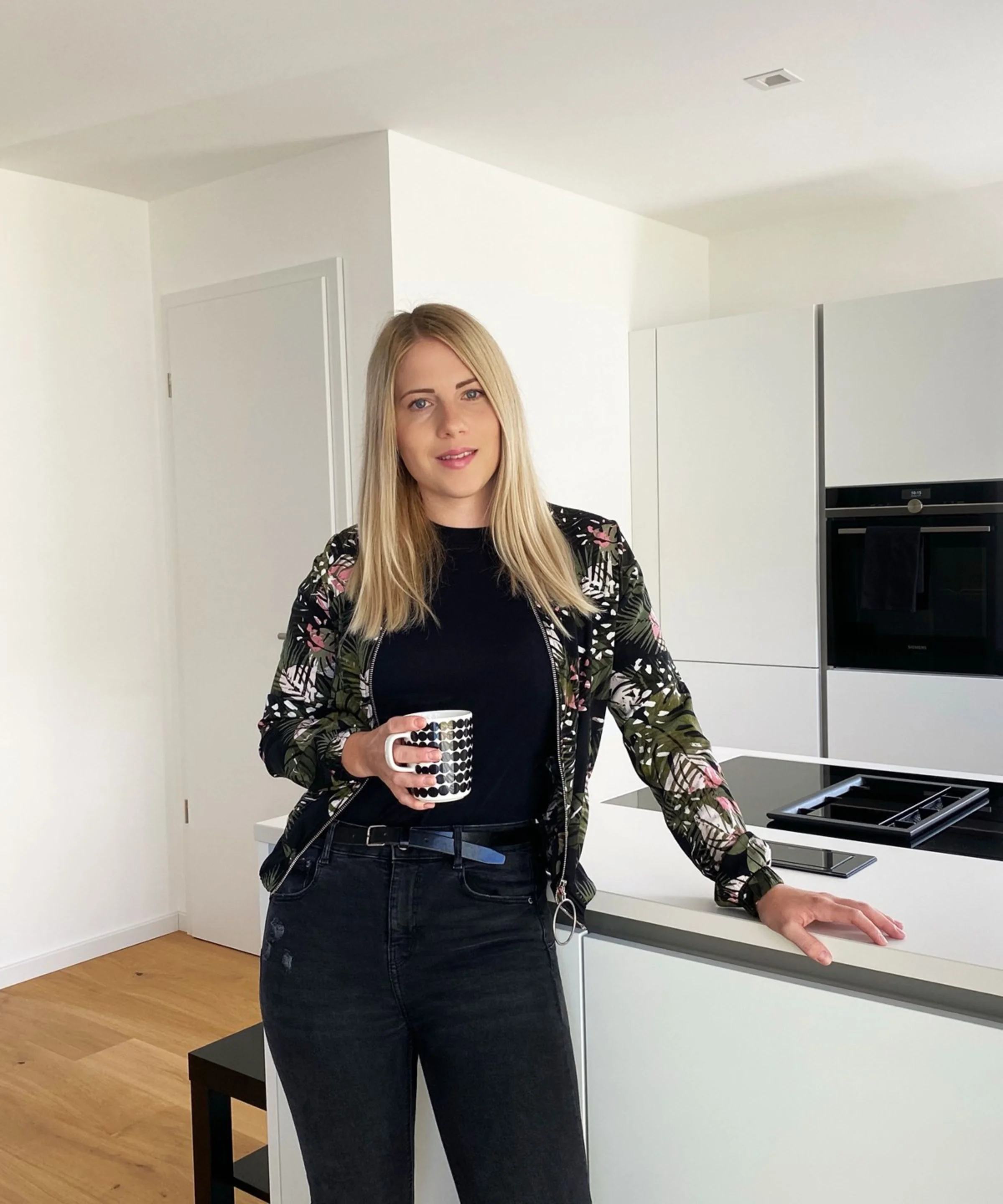 Una donna in una cucina moderna con armadi bianchi, Nolte Kitchen.