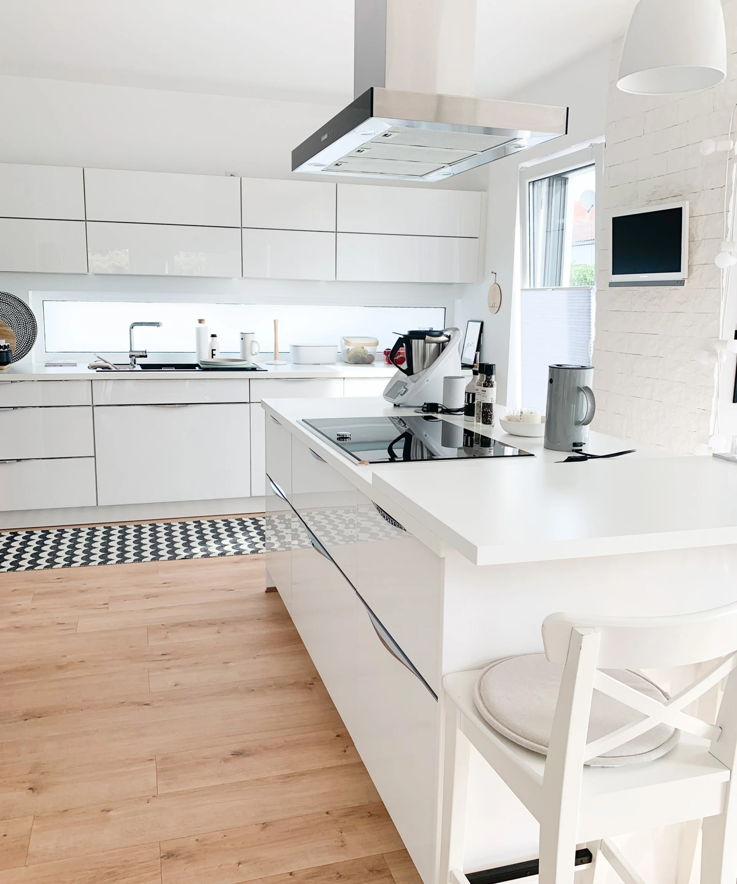 Cucina moderna e luminosa con armadi bianchi e isola; Nolte Kitchen.