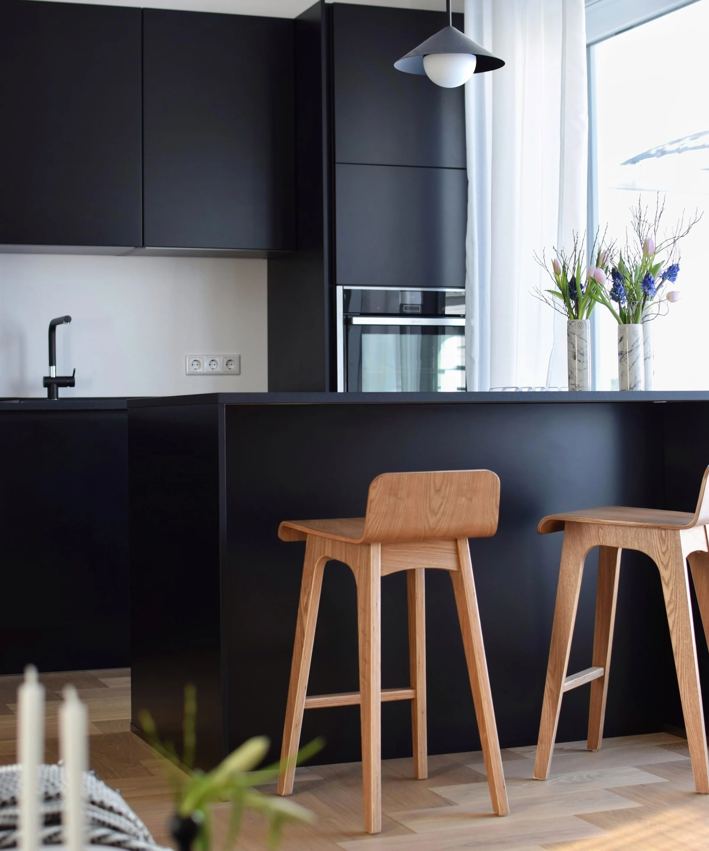 Cucina moderna con armadi neri e sedie in legno, design di Nolte Kitchen.