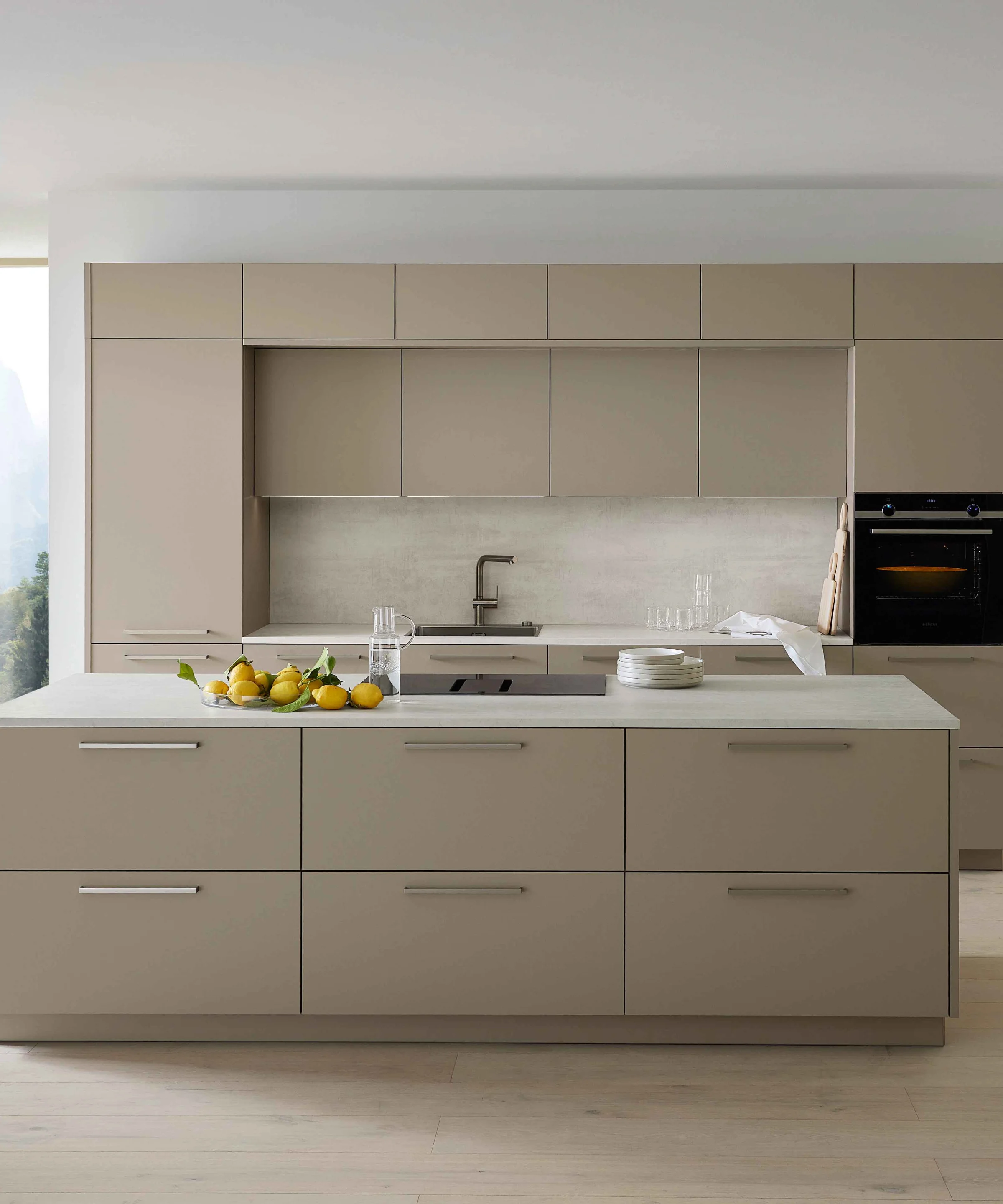 Cucina moderna con grande isola e armadi chiari, circondata da ampie finestre, Nolte Kitchen.