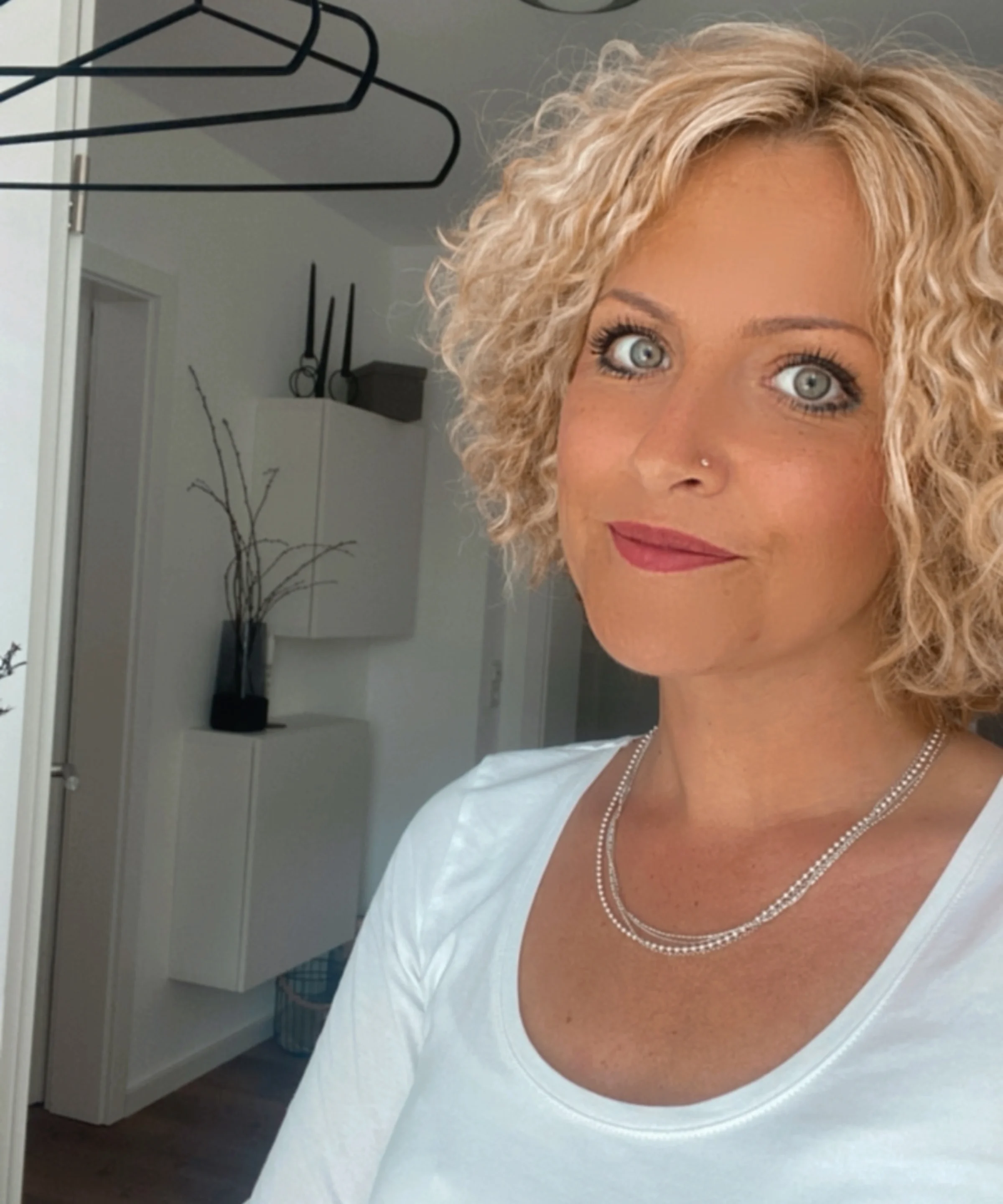 Una donna con capelli biondi ricci si trova in una stanza modernamente arredata.