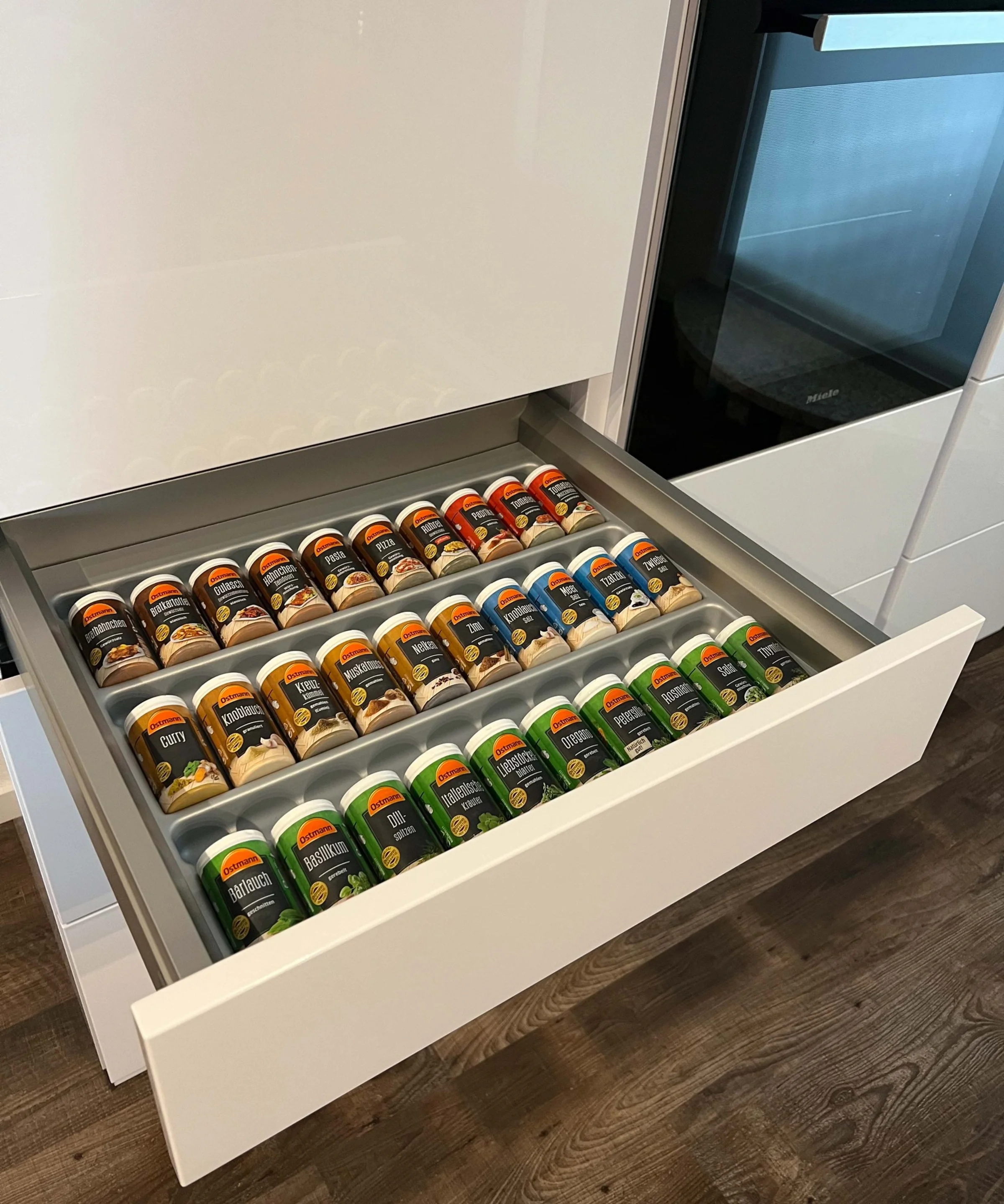 Un cassetto della cucina aperto con barattoli di spezie in un ambiente moderno di cucina Nolte.