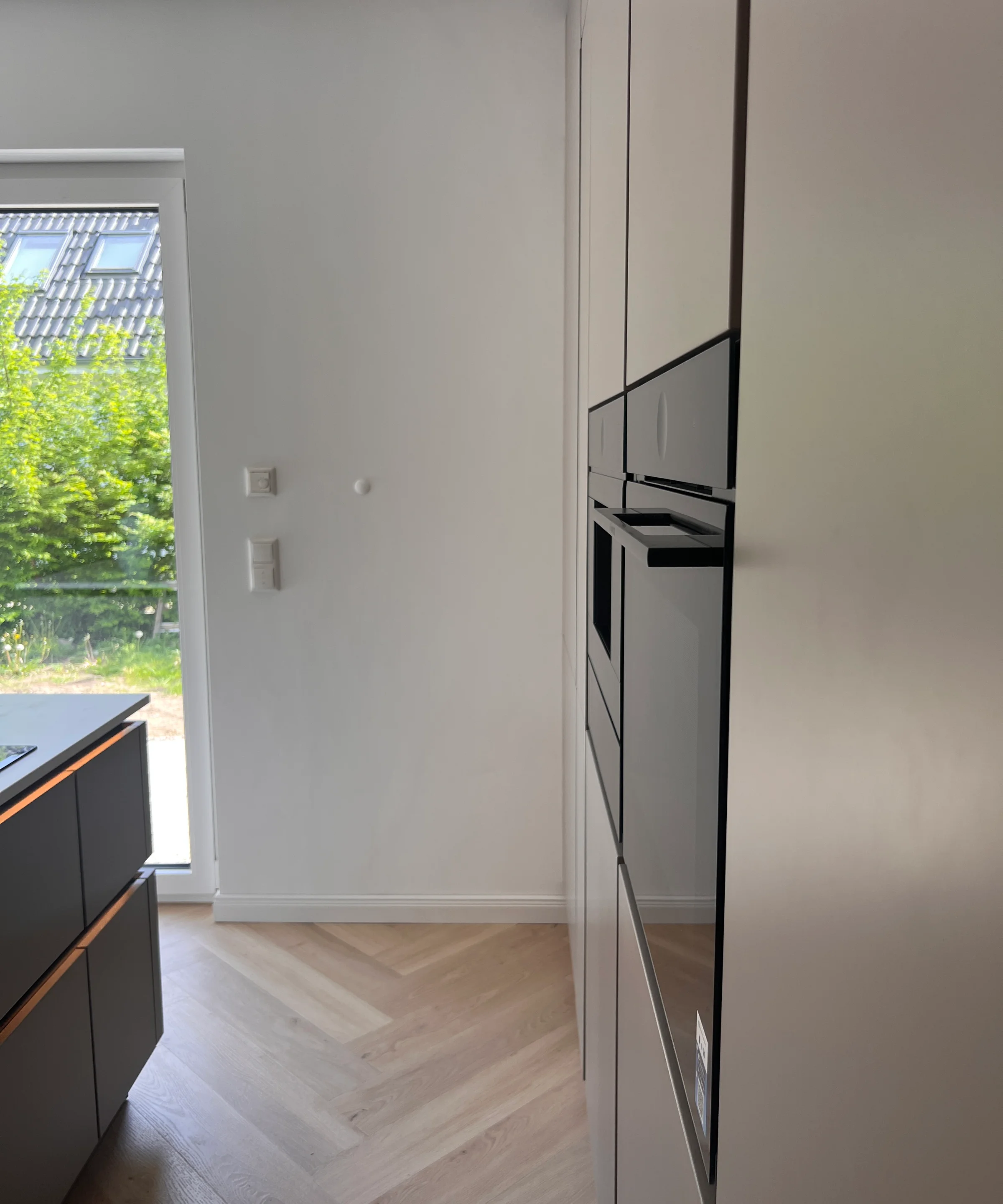 Cucina moderna con elettrodomestici integrati e pavimento in legno chiaro, design di Nolte Kitchen.