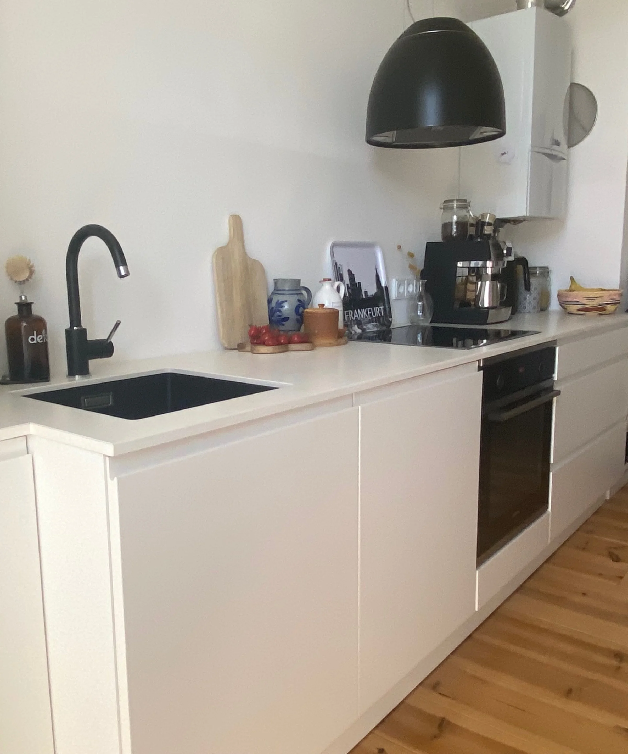 Cucina moderna con armadi bianchi e pavimento in legno, firmata Nolte Kitchen.