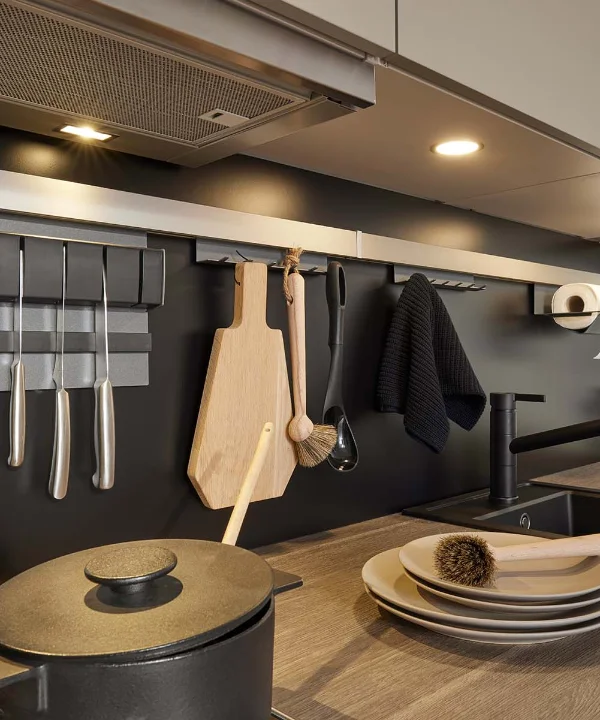 Cucina moderna con utensili appesi e stoviglie sul piano di lavoro di Nolte Kitchen.