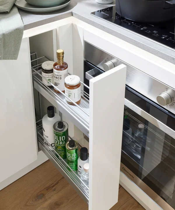Un mobile da cucina aperto con spezie e oli, accanto a un fornello. Nolte Kitchen.